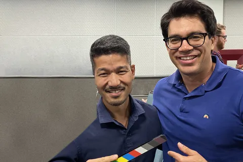 Ken Okazaki holding a clapperboard with Tai Lopez